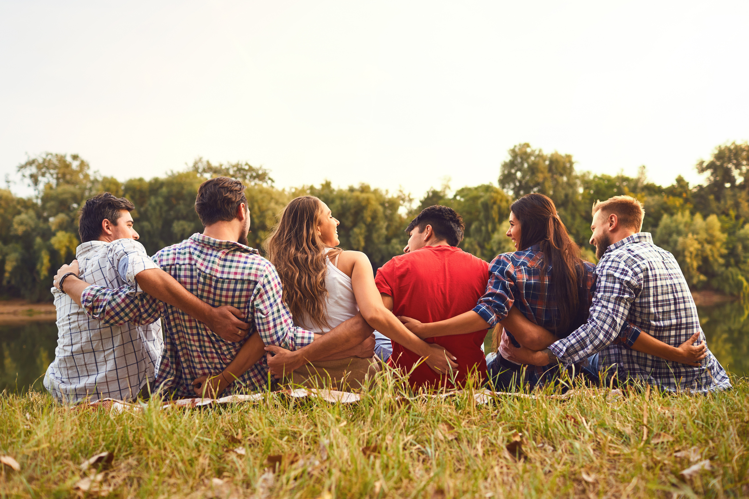 Young People Sit on the Grass Hugging in Nature in the Park